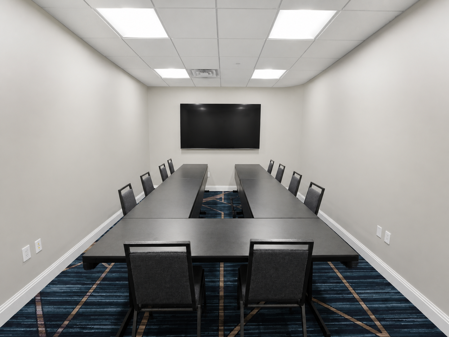 Private meeting room with conference tables and a presentation display